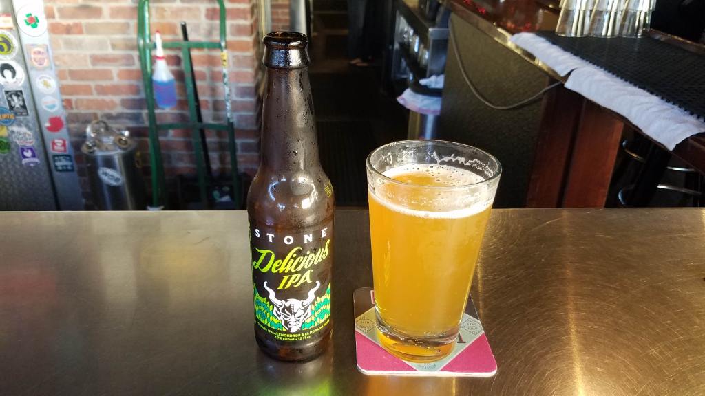 Stone Delicious IPA bottle and a pilsner full of beer from the world of beer