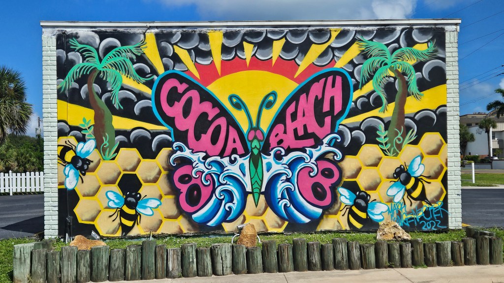 a mural of a butterfly, bees and palm trees in cocoa beach
