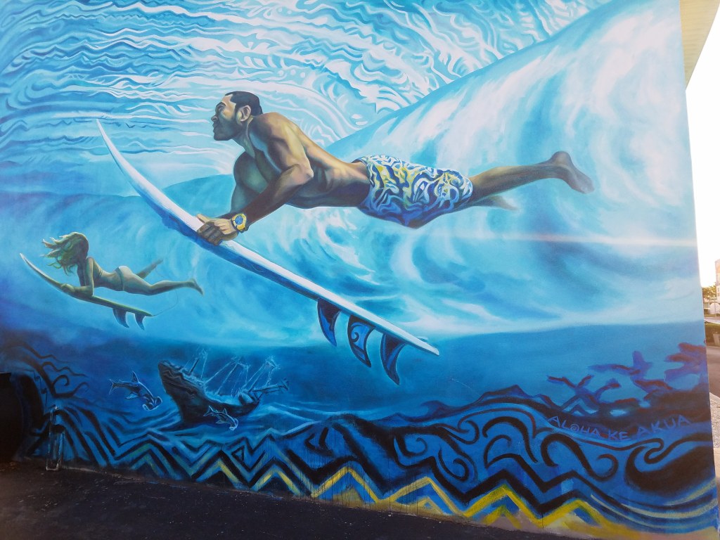A mural of a surfer and child paddling under a wave