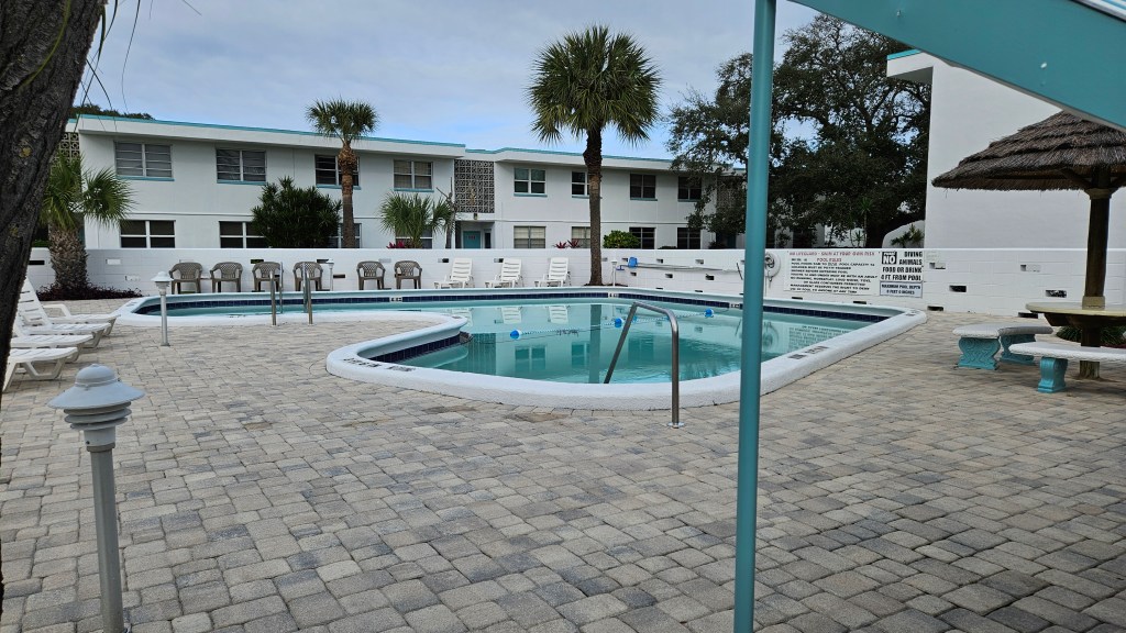 Community pool at Atlantic Gardens. Large paver pool deck with lounge chairs