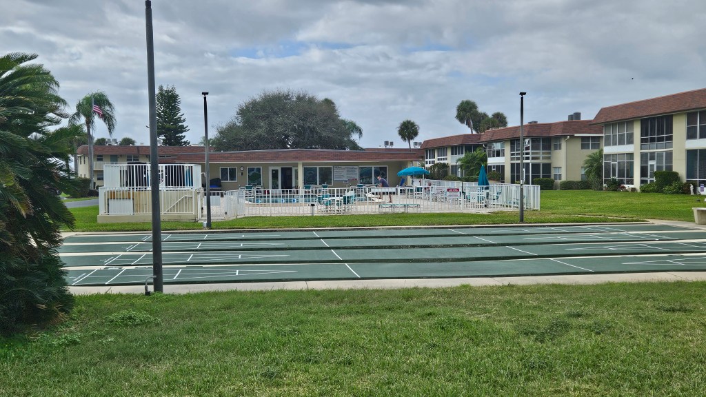 Shuffle board courts in the foreground and the community pool and clubhouse in the distance