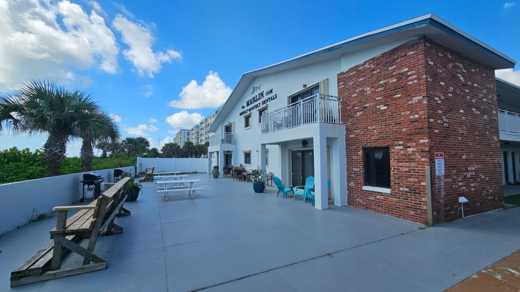 Marlin Condo patio with picnic tables, a bench, and BBQs