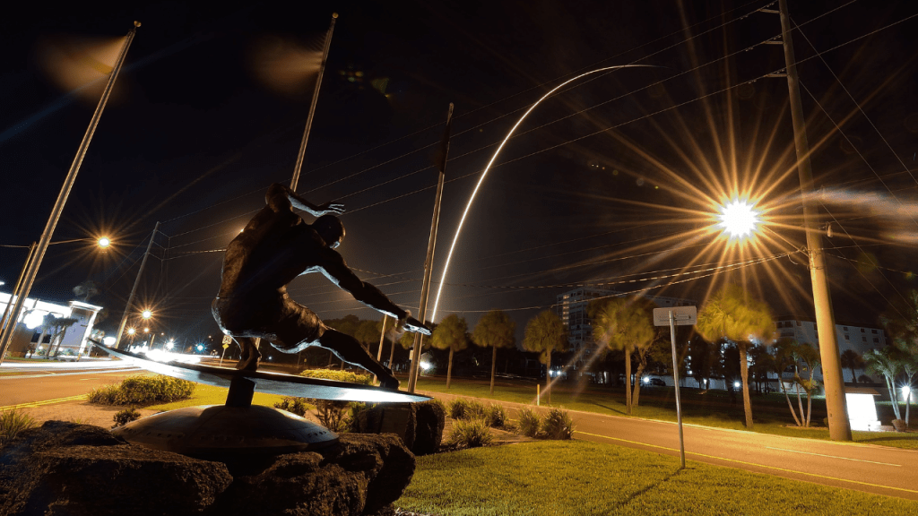 night rocket launch as seen from Cocoa Beach. Kelly Slater Statue is in the foreground